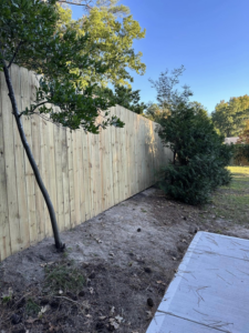 A newly installed wood privacy fence extending along a property line by First in Fencing and Remodeling in Fayetteville, NC.