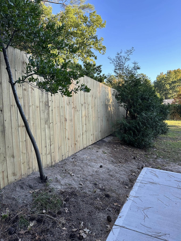 A newly installed wood privacy fence extending along a property line by First in Fencing and Remodeling in Fayetteville, NC.