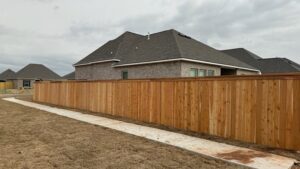 A long wood privacy fence installed along a sidewalk in a residential neighborhood by C & M Affordable Fence, LLC in Haughton, LA