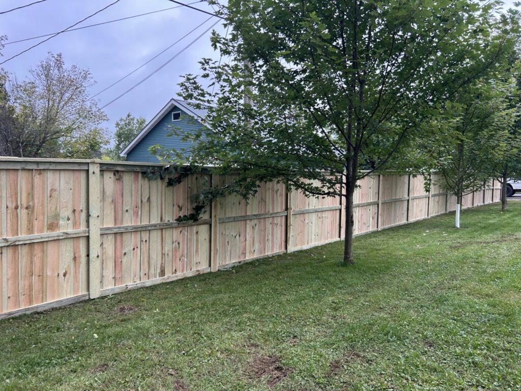 A long wooden privacy fence installed along a street by North Shore Fence Company in Centereach, NY.