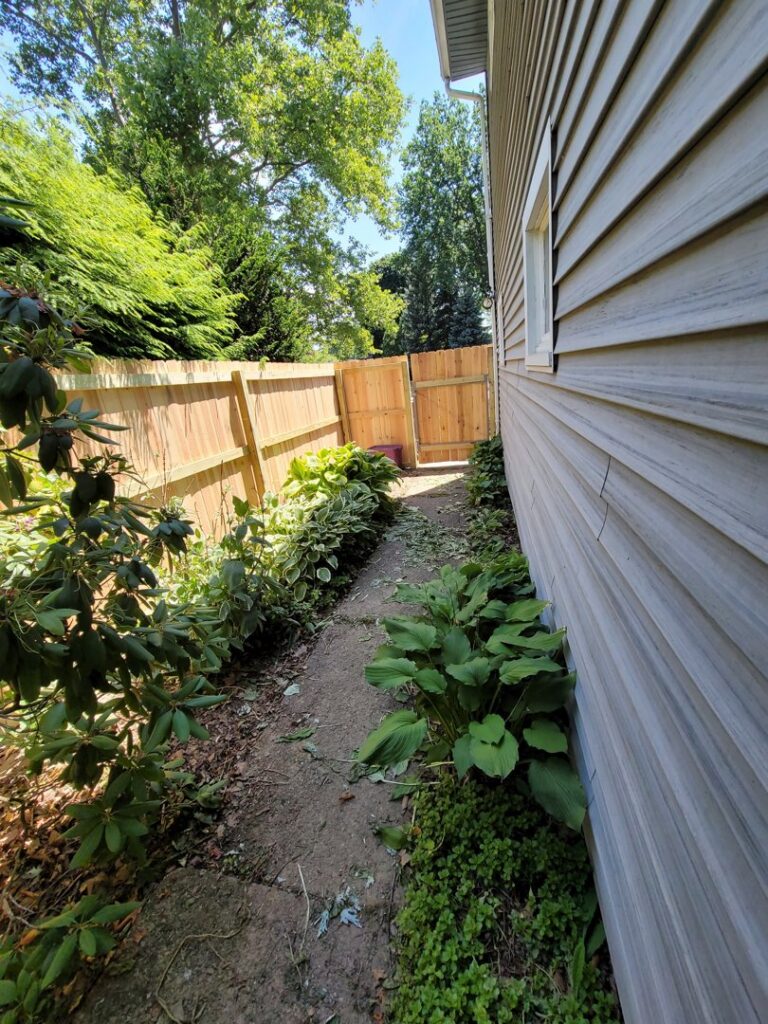 A wood privacy fence with a gate installed along a narrow side yard by Camp Carlson Fencing in Rochester, NY.