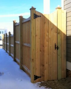 A sturdy wood privacy fence with a gate installed next to a house during winter by Raatz Fence Company in Louisville, KY.