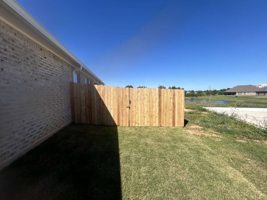 A new wood privacy fence and gate installed alongside a brick house by C & M Affordable Fence, LLC in Haughton, LA