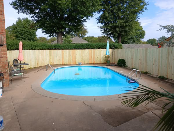 A new wooden privacy fence installed around a swimming pool by Master Fence Builders in Fort Smith, AR.