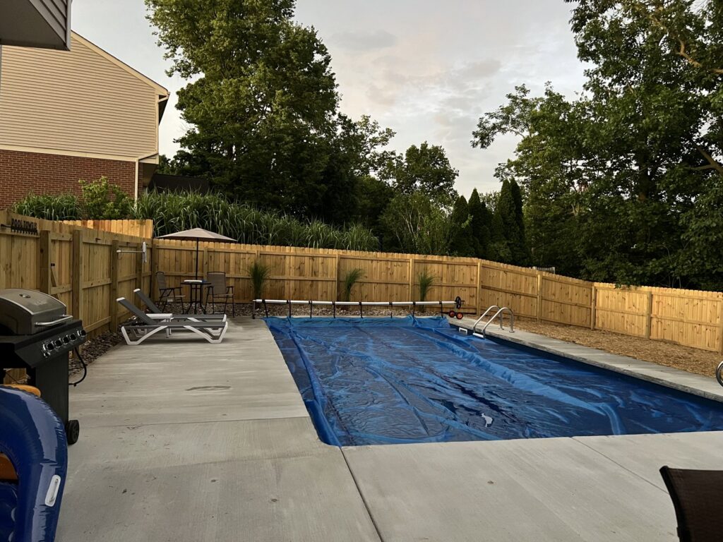 A newly installed wood privacy fence enclosing a backyard with a swimming pool by Superior Fence & Rail of Northern Kentucky in Florence, KY.