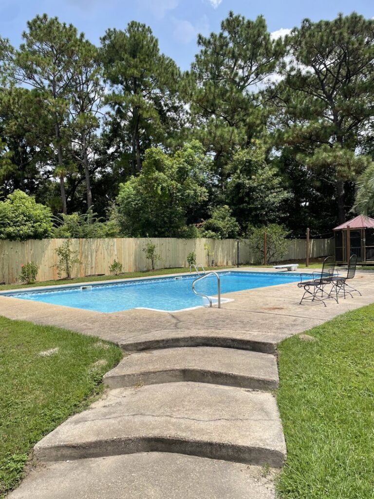 A wooden privacy fence installed around a swimming pool area by Jaguar Fence LLC in Mobile, AL.