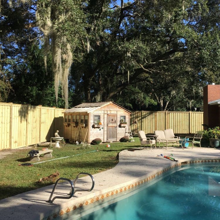 A newly installed wood privacy fence enclosing a backyard with a swimming pool and shed by Superior Fence and Rail of Little Rock, AR