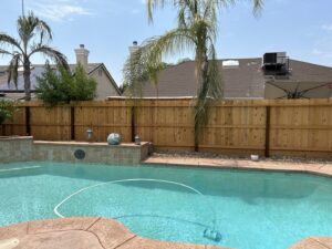 A sturdy wood privacy fence surrounding a residential backyard with a pool, built by The Fence Company in Fresno, CA.