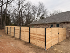 A new wood privacy fence with black posts and a gate installed by Old School Fence Co. in Springfield, MO.