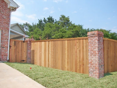 A custom wood privacy fence with brick pillars and a matching gate installed by D-Fence of Tulsa in Tulsa, OK.