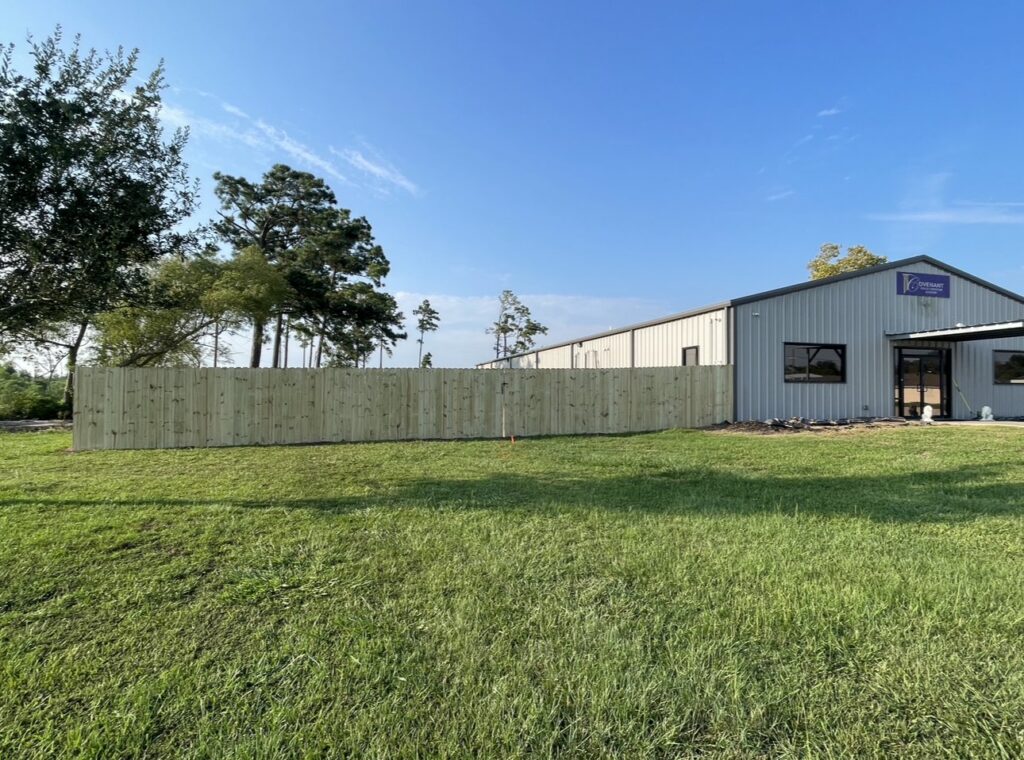 A new wooden privacy fence installed alongside a commercial building by JH Fencing in Lawrence, KS.