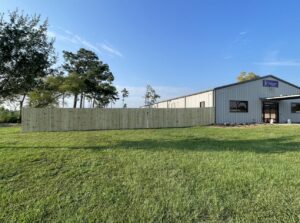 A new wooden privacy fence installed alongside a commercial building by JH Fencing in Lawrence, KS.