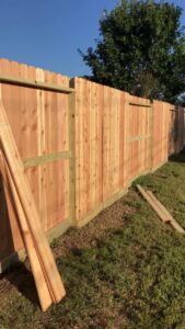 A wood privacy fence under construction, with panels ready for installation by GOAT Fence Company in Houston, TX.