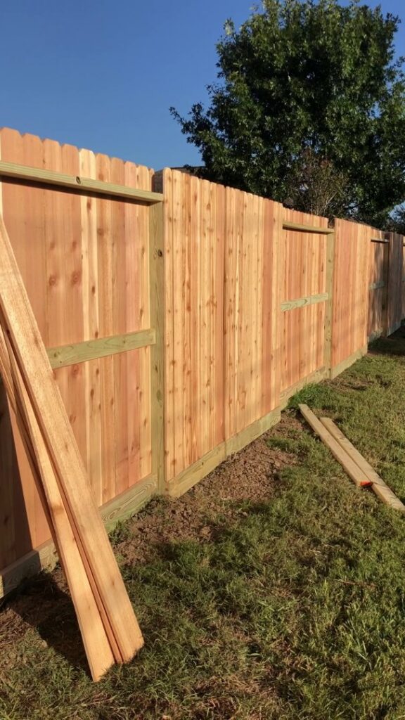 A wood privacy fence under construction, with panels ready for installation by GOAT Fence Company in Houston, TX.