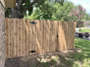A new wooden privacy fence with a double gate and decorative hinges, installed by Master Fence Builders in Fort Smith, AR.