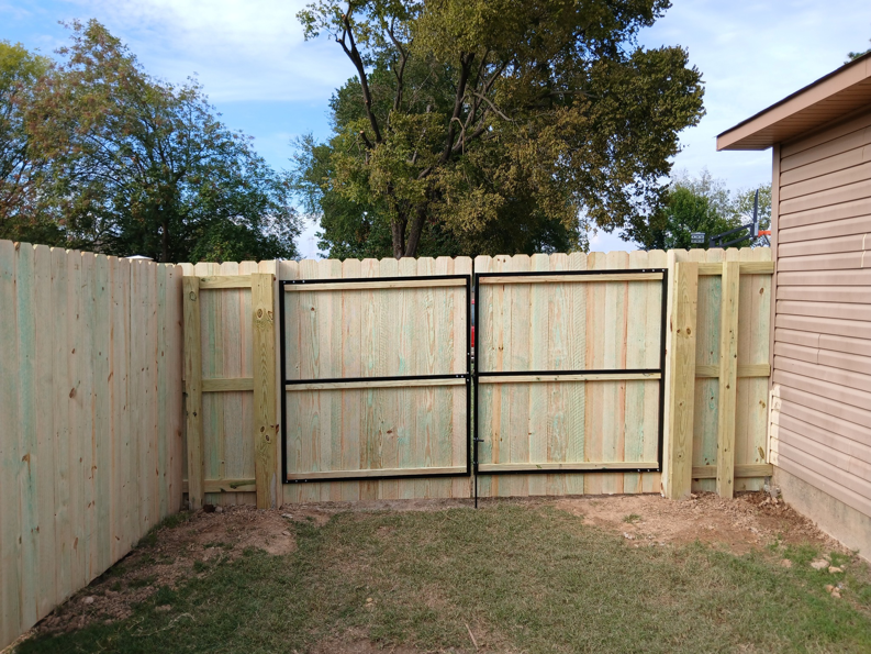 A new wooden privacy fence with a sturdy double gate, installed by Master Fence Builders in Fort Smith, AR.
