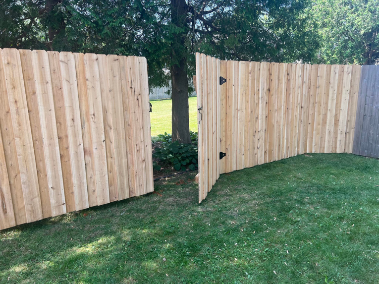 A newly installed wood privacy fence with a double gate in a residential yard by Northern Fence, Inc. in Appleton, WI.