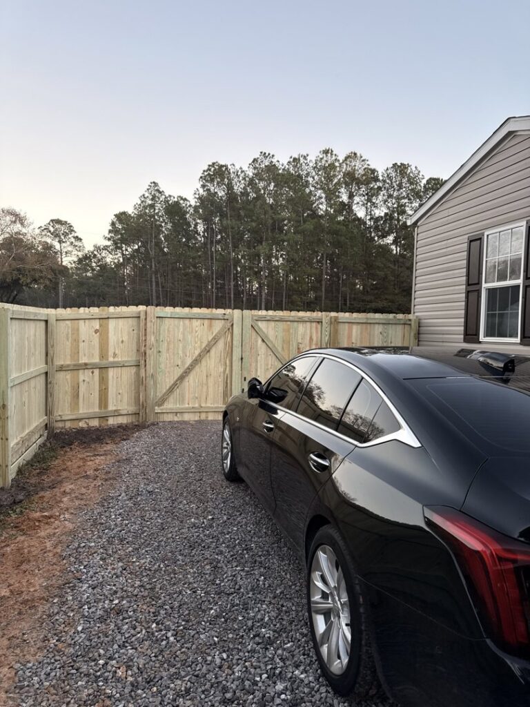 A newly installed wood privacy fence with a double gate for a residential property by FenceCo LLC in Pass Christian, MS.