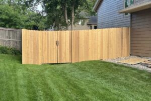 A new wooden privacy fence with a double gate installed in a residential yard by The GateKeeper Perimeter Fence & Automated Security in Sioux Falls, SD