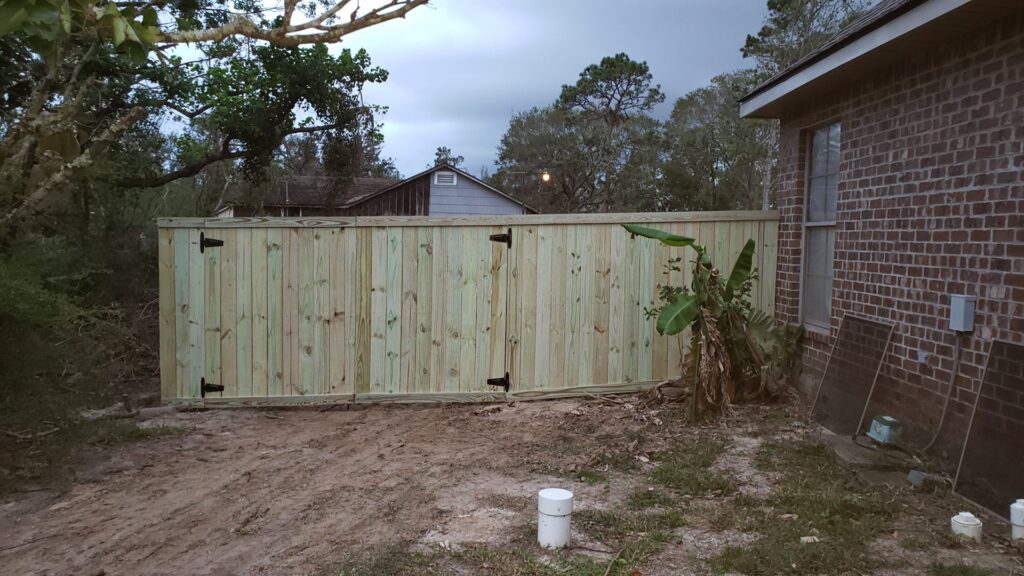 A sturdy wooden privacy fence featuring two functional gates, installed by JH Fencing in Lawrence, KS.