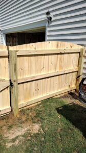 A custom wood privacy fence gate installed next to a house by Aguilarfence services LLC in Clayton, NC.