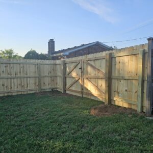 A newly installed wood privacy fence with a gate in a residential backyard by Frontier Fence LLC Bowling Green,Ky