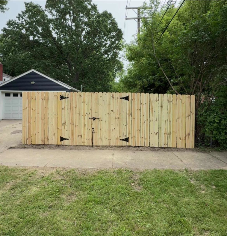 A newly installed wood privacy fence with a gate across a driveway by Final Touch Fencing LLC in Macomb Township, MI.