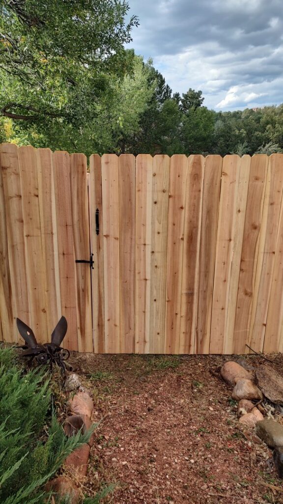 A newly installed wood privacy fence with a single gate, showcasing the work of Good Neighbor Fencing, LLC in Colorado Springs, CO.