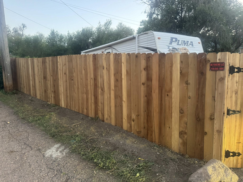 A newly installed wood privacy fence with a gate by HG Fencing LLC in Fountain, CO.