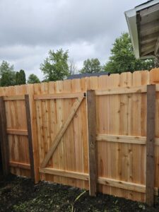 A newly installed wood privacy fence with a gate, showcasing quality craftsmanship by JM Fence Works in Davenport, IA.