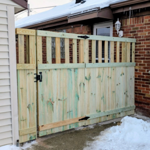 A newly installed wood privacy fence section with a gate and black hardware by Mjölnir Design in Milwaukee, WI.