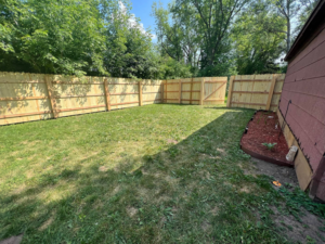 A newly installed wood privacy fence with a gate leading to a residential property by Northern Fence, Inc. in Appleton, WI.