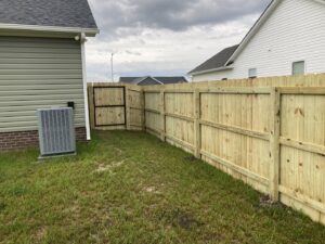 A wood privacy fence with a gate installed next to a residential home by Sea Level Fence in Harbinger, NC