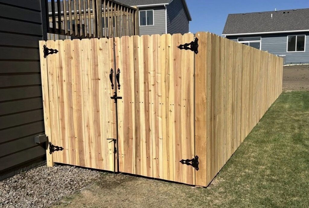 A new wooden privacy fence with a decorative gate installed by The GateKeeper Perimeter Fence & Automated Security in Sioux Falls, SD