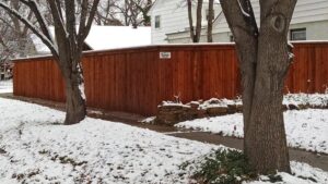 A long wood privacy fence standing strong in a snowy residential area, installed by Pro Insulation and Fence in Wichita Falls, TX.