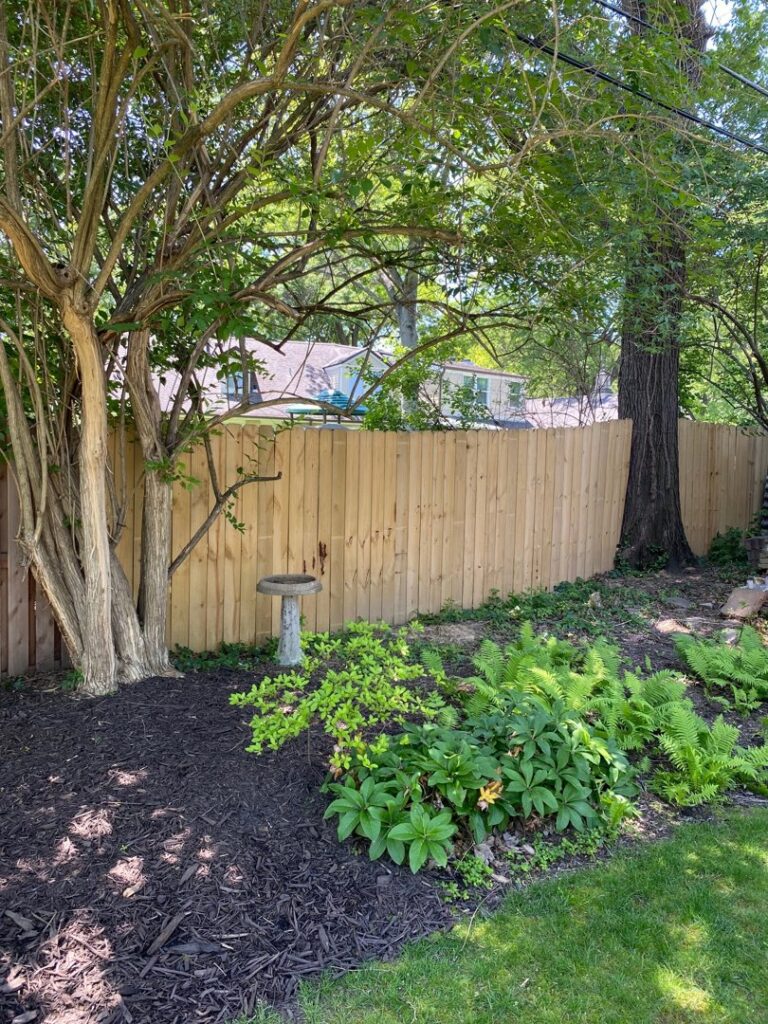 A newly installed wood privacy fence complementing backyard landscaping by Exterior Experience LLC in St. Louis, MO.