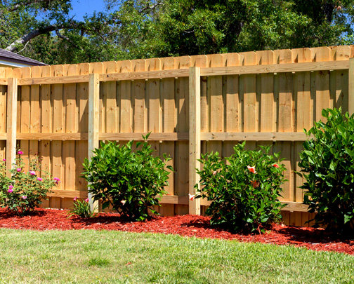 A sturdy wood privacy fence with decorative landscaping installed by Superior Fence & Rail of Charlotte, NC