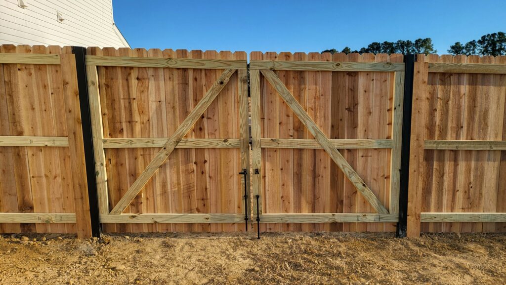 A new wood privacy fence featuring a large double gate, installed by Fayetteville Fence Pros in Fayetteville, NC.