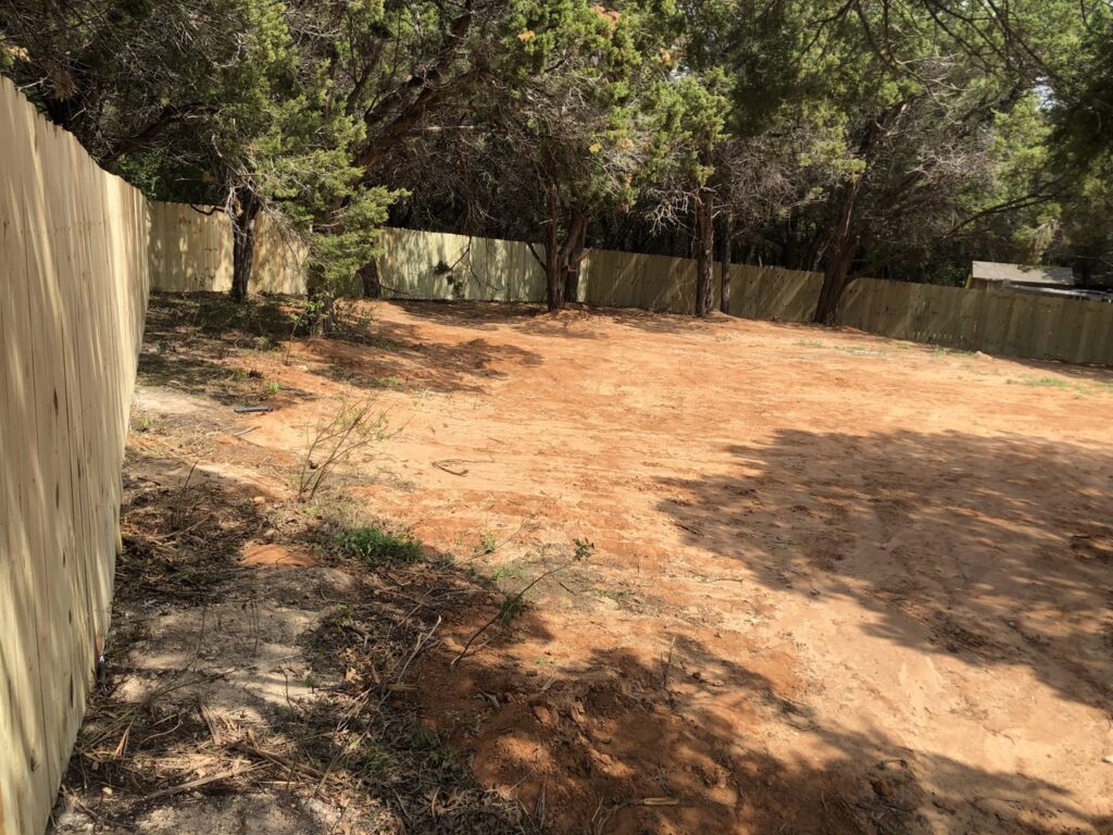 A long wood privacy fence enclosing a large dirt lot, installed by Backyard Builders in Rockford, MI.