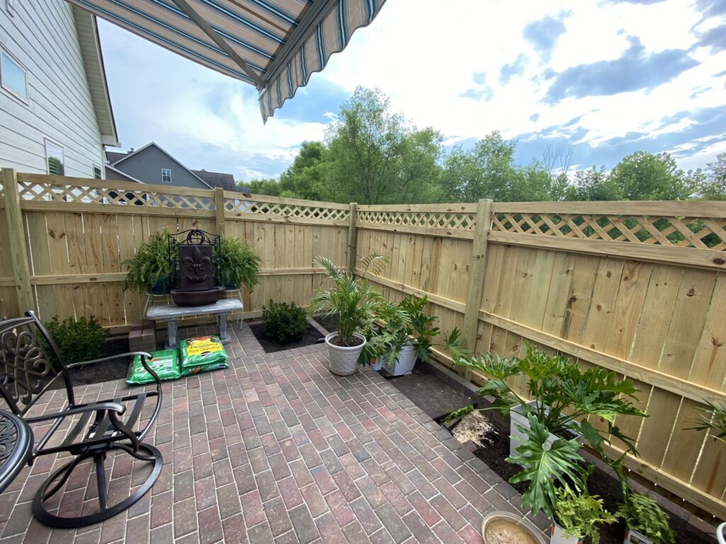 A wood privacy fence with a lattice top enclosing a cozy outdoor patio area, installed by Holmes Fence Company in Chattanooga, TN.