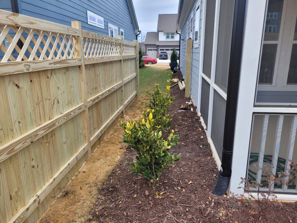 A new wood privacy fence with a decorative lattice top installed between two homes by Endurance Fence Solutions, LLC in Holly Springs, NC