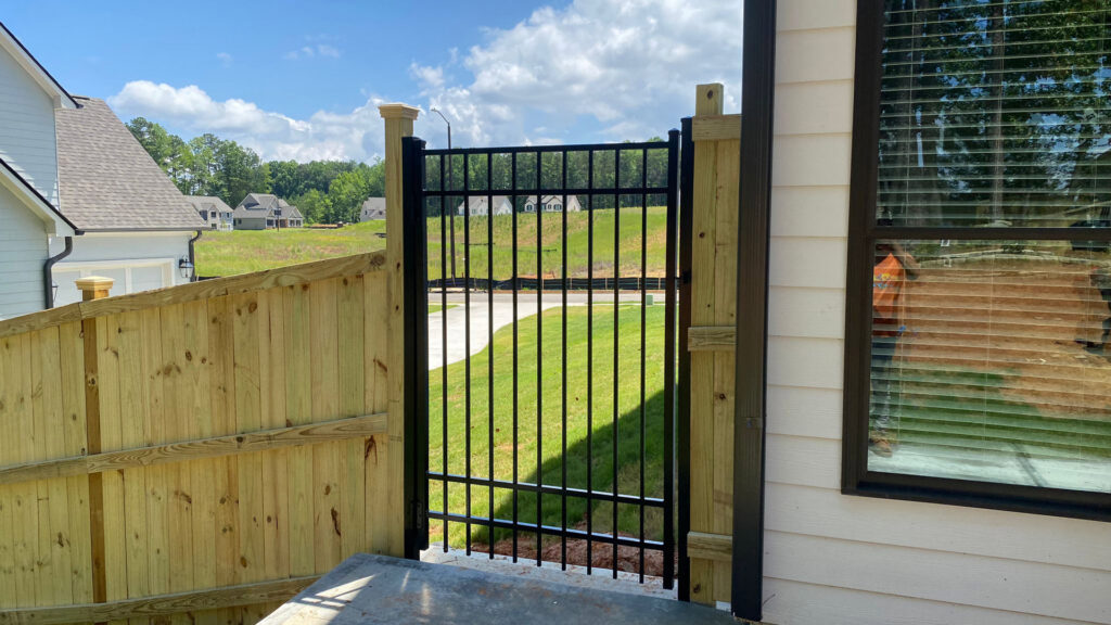 A new wood privacy fence with a black metal gate installed by Hawk Fences LLC in Johns Creek, GA.