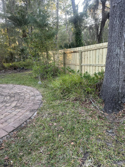 A newly installed wood privacy fence next to a brick patio, installed by R&R Fence Services in Jacksonville, FL.