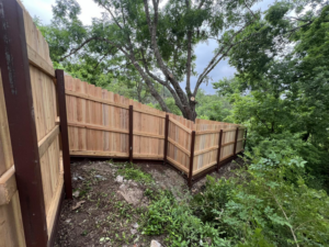A custom wood privacy fence expertly installed on challenging sloped terrain by K.K. Landscaping & Fencing in Austin, TX.