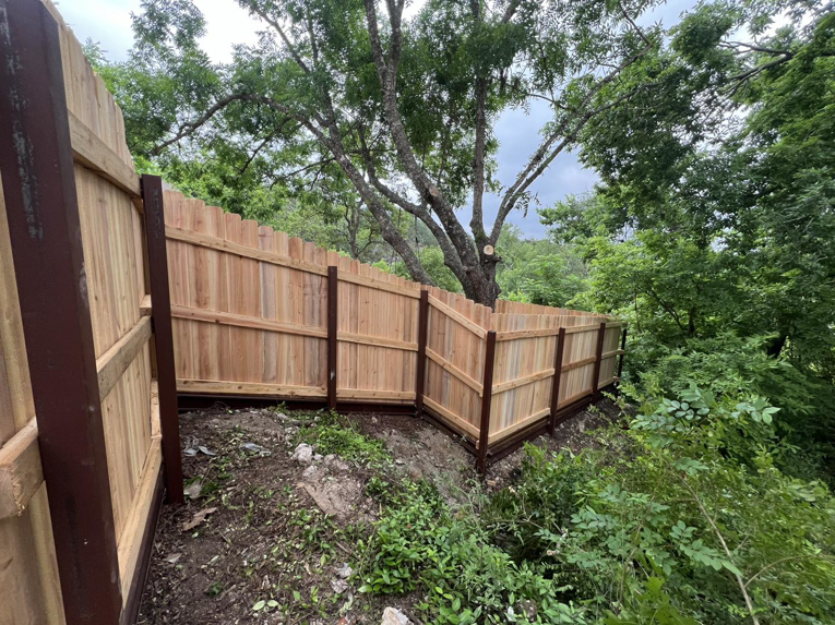 A custom wood privacy fence expertly installed on challenging sloped terrain by K.K. Landscaping & Fencing in Austin, TX.