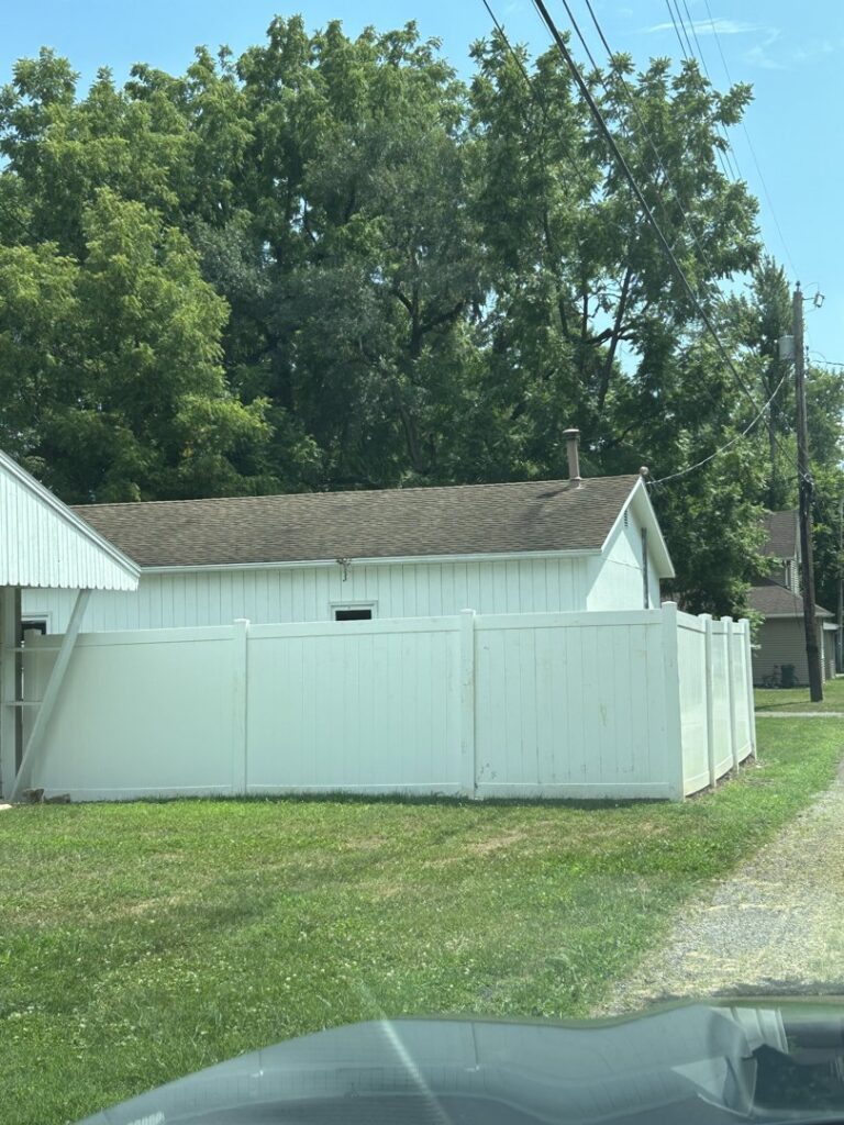 A long wood privacy fence installed on sloped terrain with visible bracing by Render Fences in Fishers, IN.