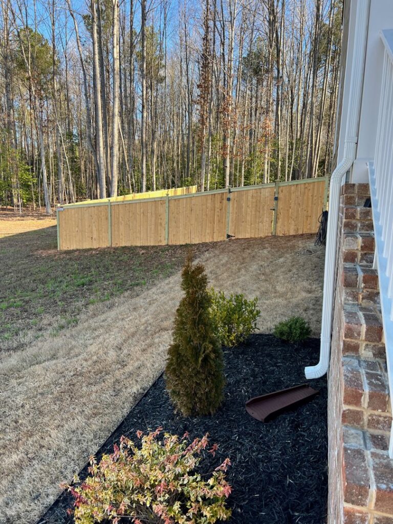 A sturdy wood privacy fence expertly installed on a sloped backyard by Aguilarfence services LLC in Clayton, NC.