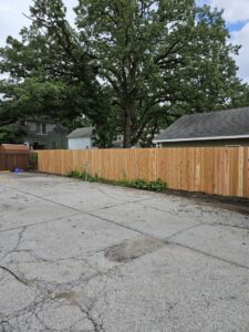 A long wooden privacy fence separating a parking lot from a residential area, installed by JM Fence Works in Davenport, IA.