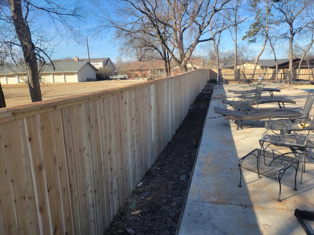 A new wood privacy fence installed next to a patio area by Veteran Fence Company LLC in Shawnee, OK.