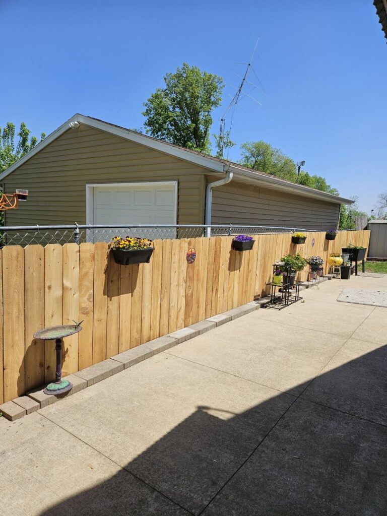 A newly installed wood privacy fence along a concrete patio with flower boxes by Corridor Residential Fencing Co. in Cedar Rapids, IA.